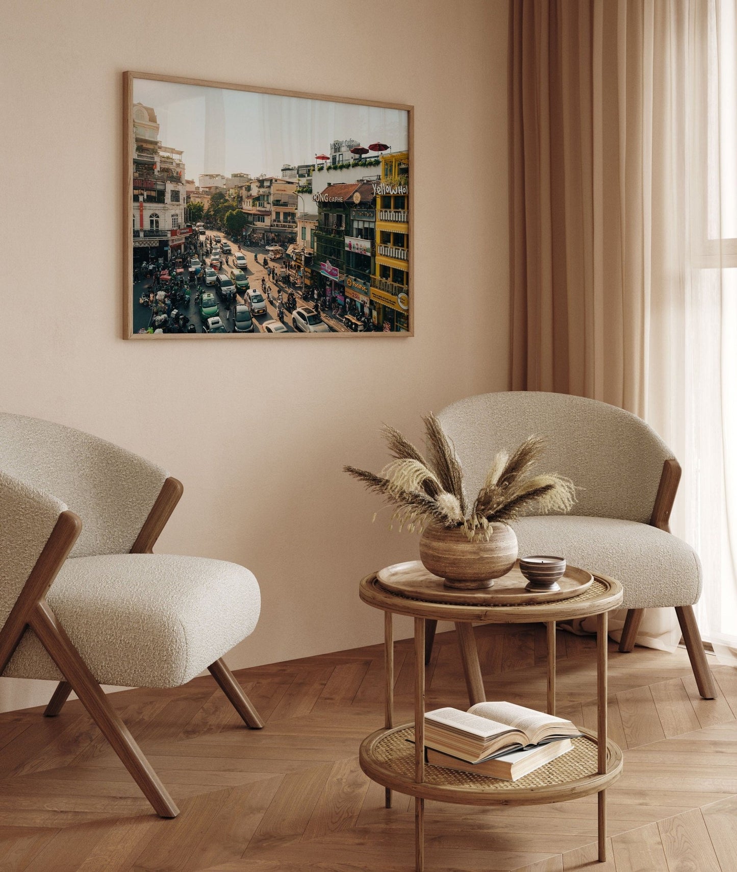 Minimalist living room with two beige chairs, a round wooden table, and Streets of Hanoi wall art.