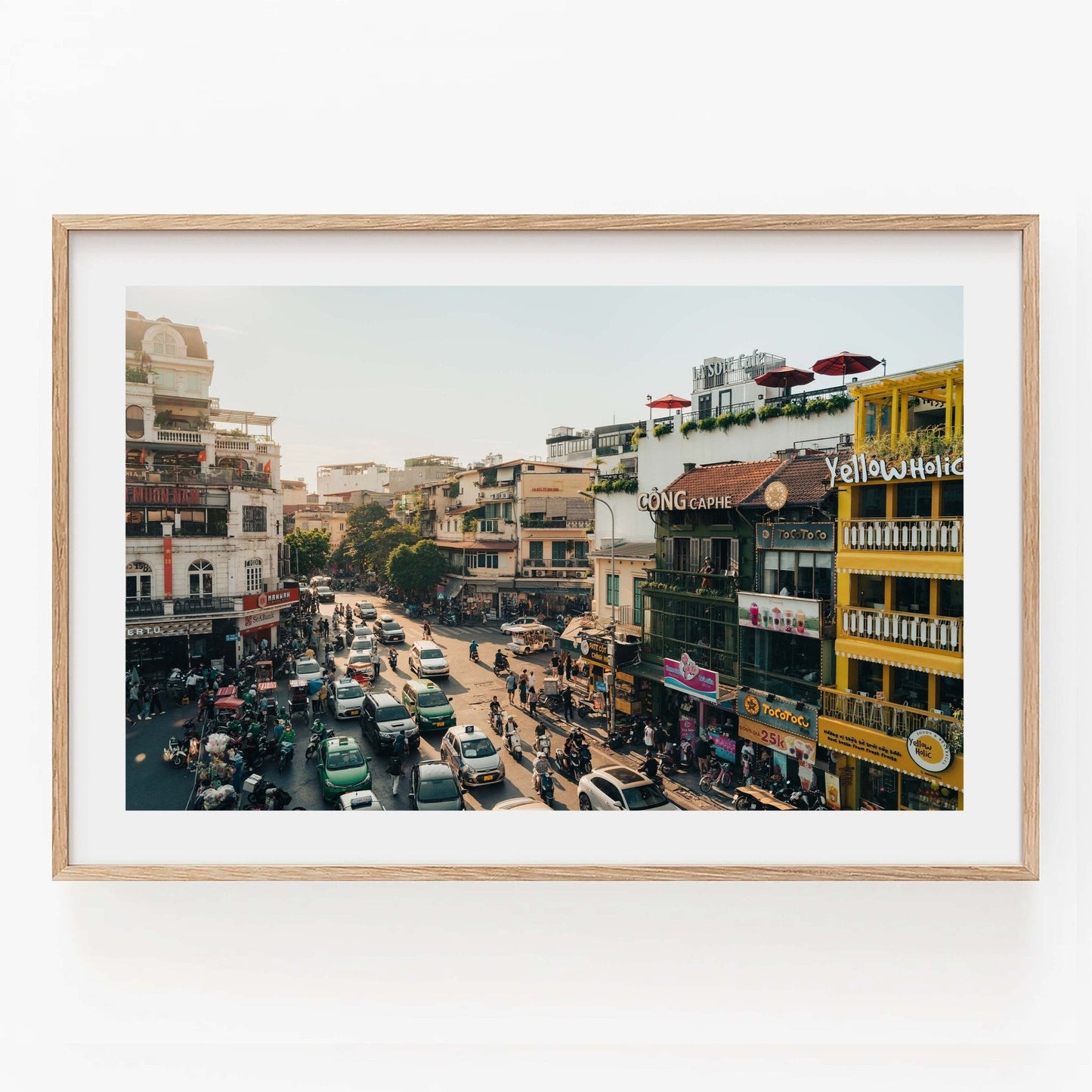 Framed Streets of Hanoi photo showing a bustling street with buildings, cars, and pedestrians.
