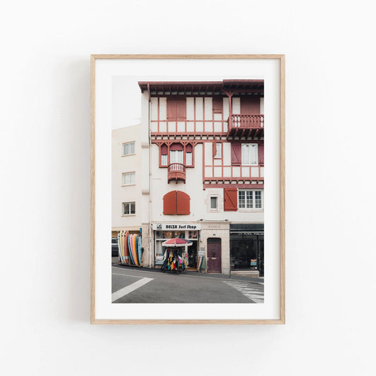 Framed photo titled Surf Shop depicting a street corner with surfboards and vibrant architecture.