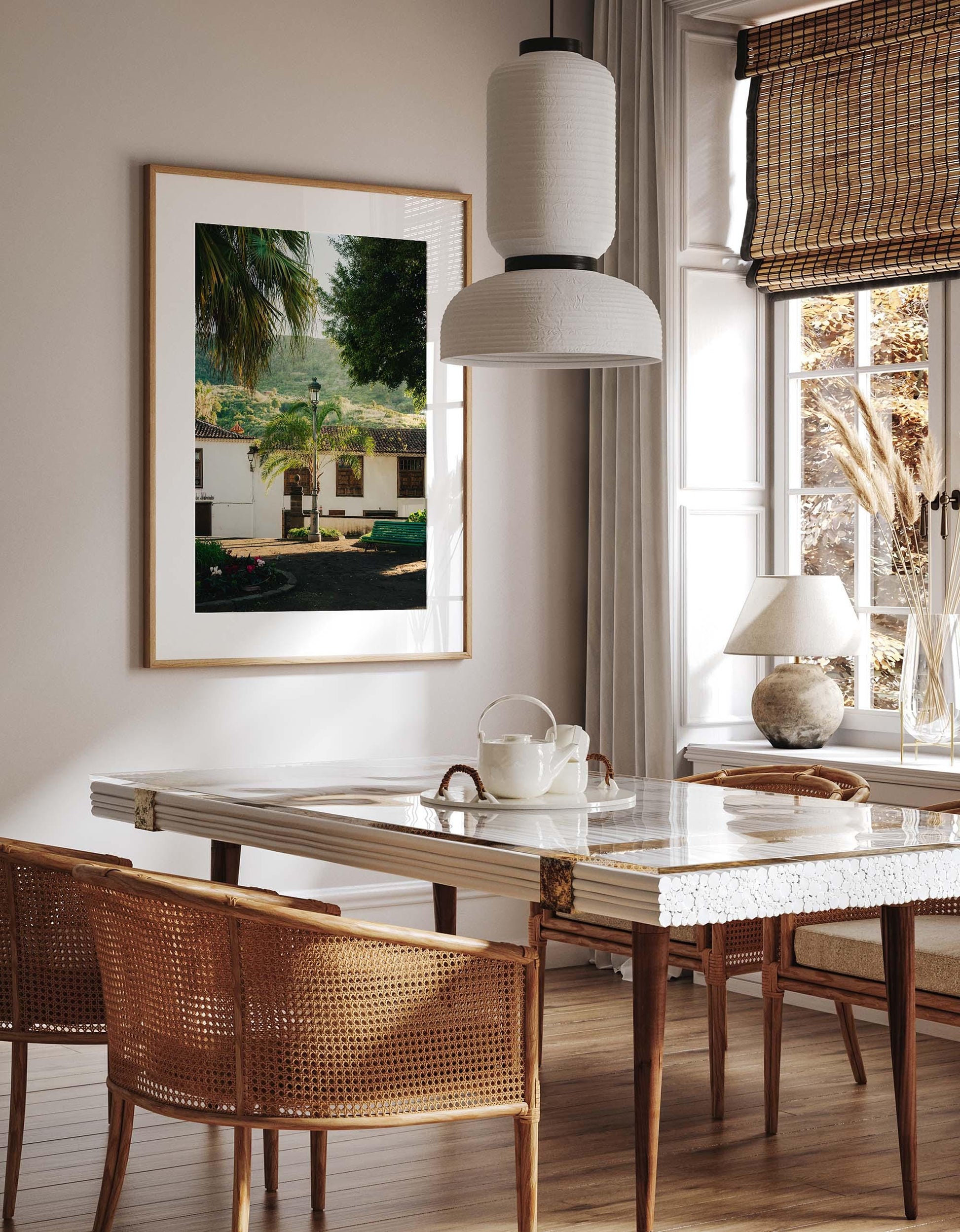 Bright dining room with a marble table, rattan chairs, and Tenerife Garden framed art on the wall.