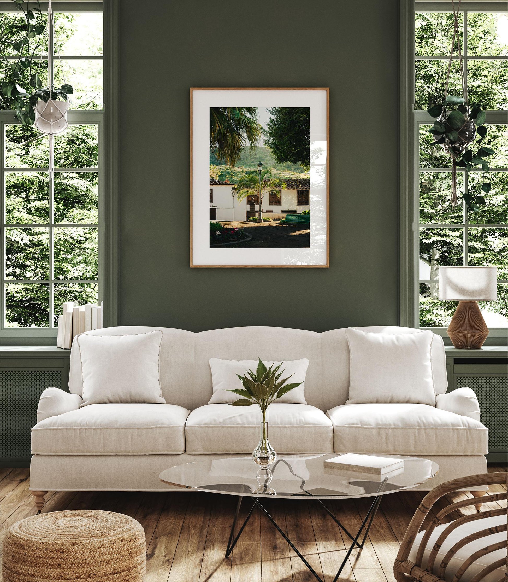 A cozy living room with the Tenerife Garden white sofa, glass coffee table, large windows, and art on a green wall.