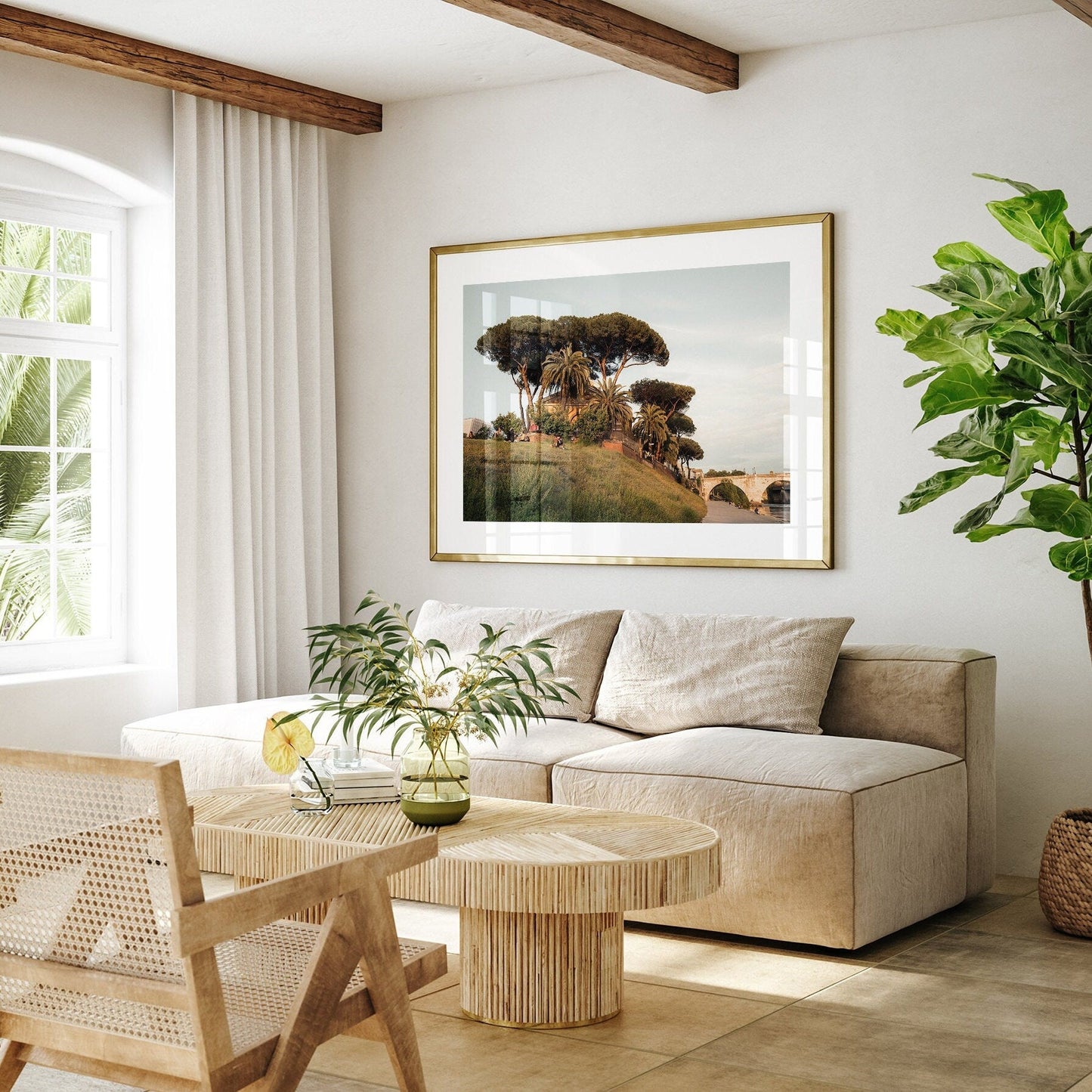Bright living room with Tiber Island Delight I, a beige sofa, wooden table, wicker chair, and a large green plant.