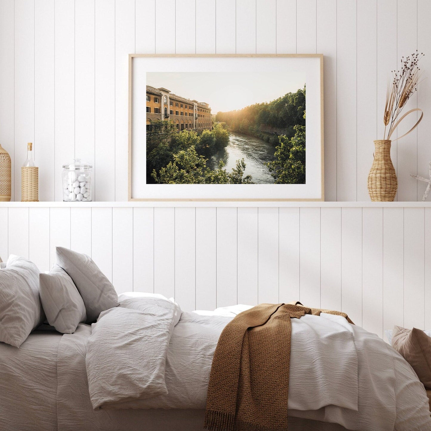 Cozy bedroom with white walls, a bed, and Tiber Island Glow II above a shelf with decorative vases.