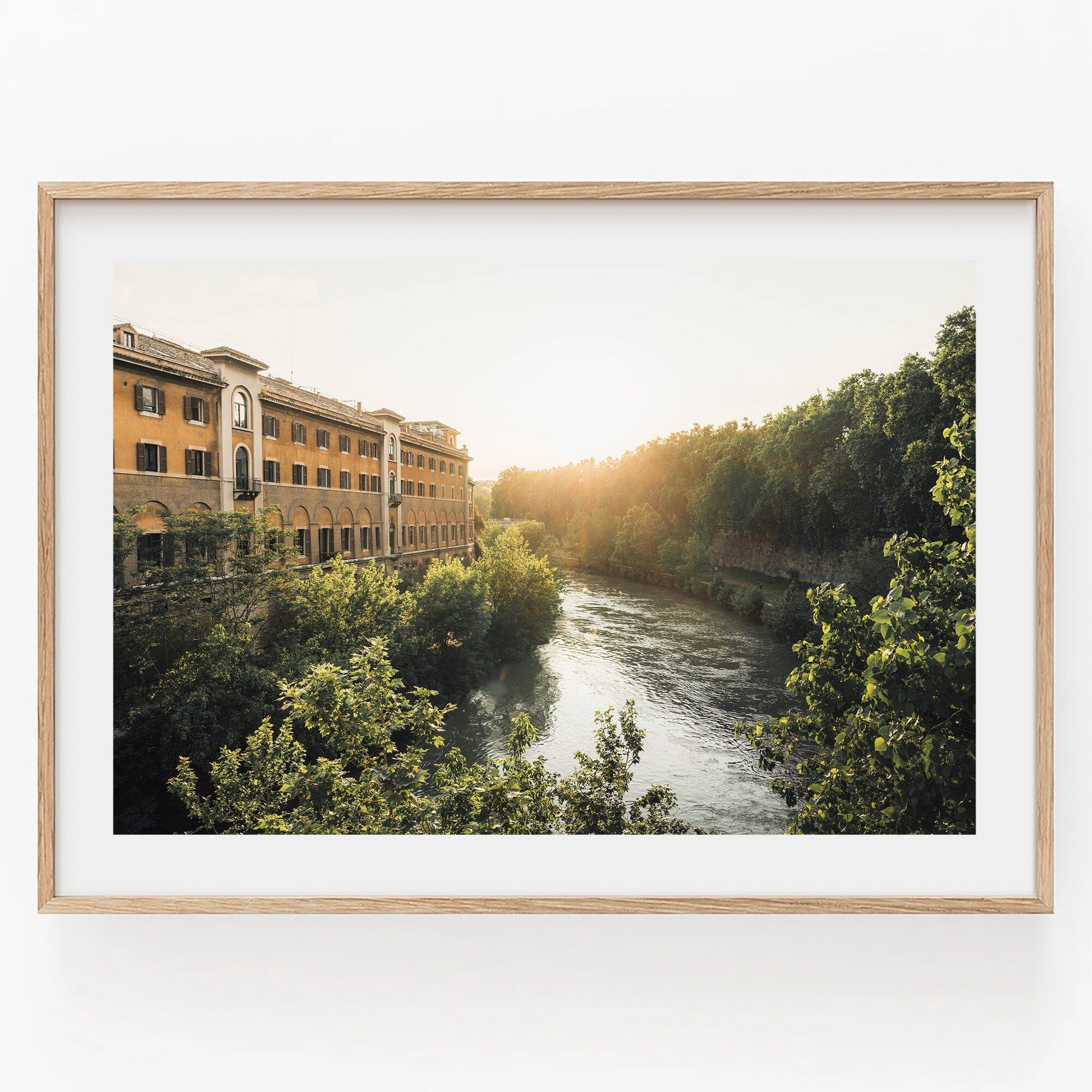 Framed Tiber Island Glow II photo of a river by a building and forest in soft sunlight.