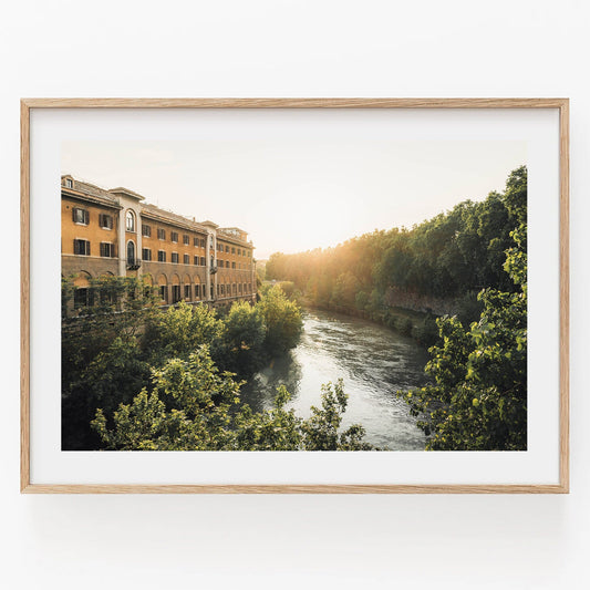 Framed Tiber Island Glow II photo of a river by a building and forest in soft sunlight.