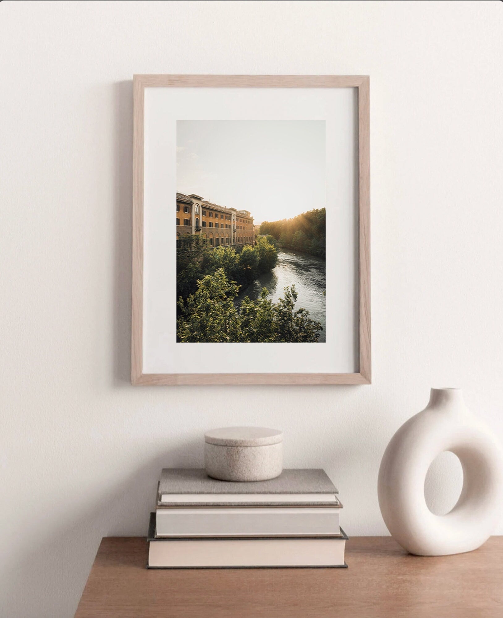 Tiber Island Glow landscape photo framed above a wooden table with books and a ceramic vase.