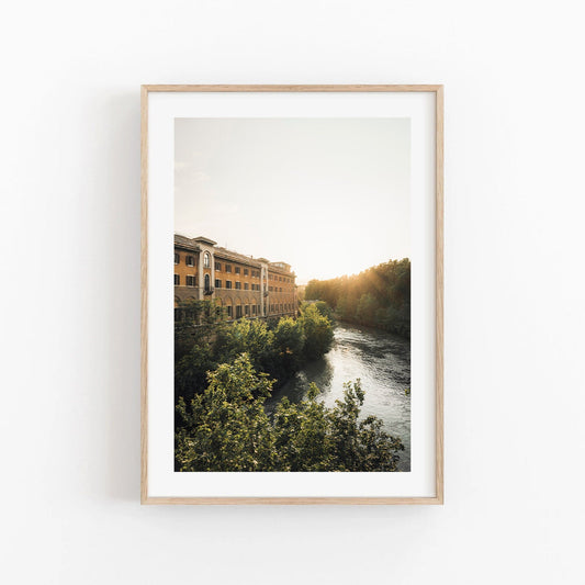 Tiber Island Glow: Framed photo of a riverside building at sunset, surrounded by trees and a flowing river.