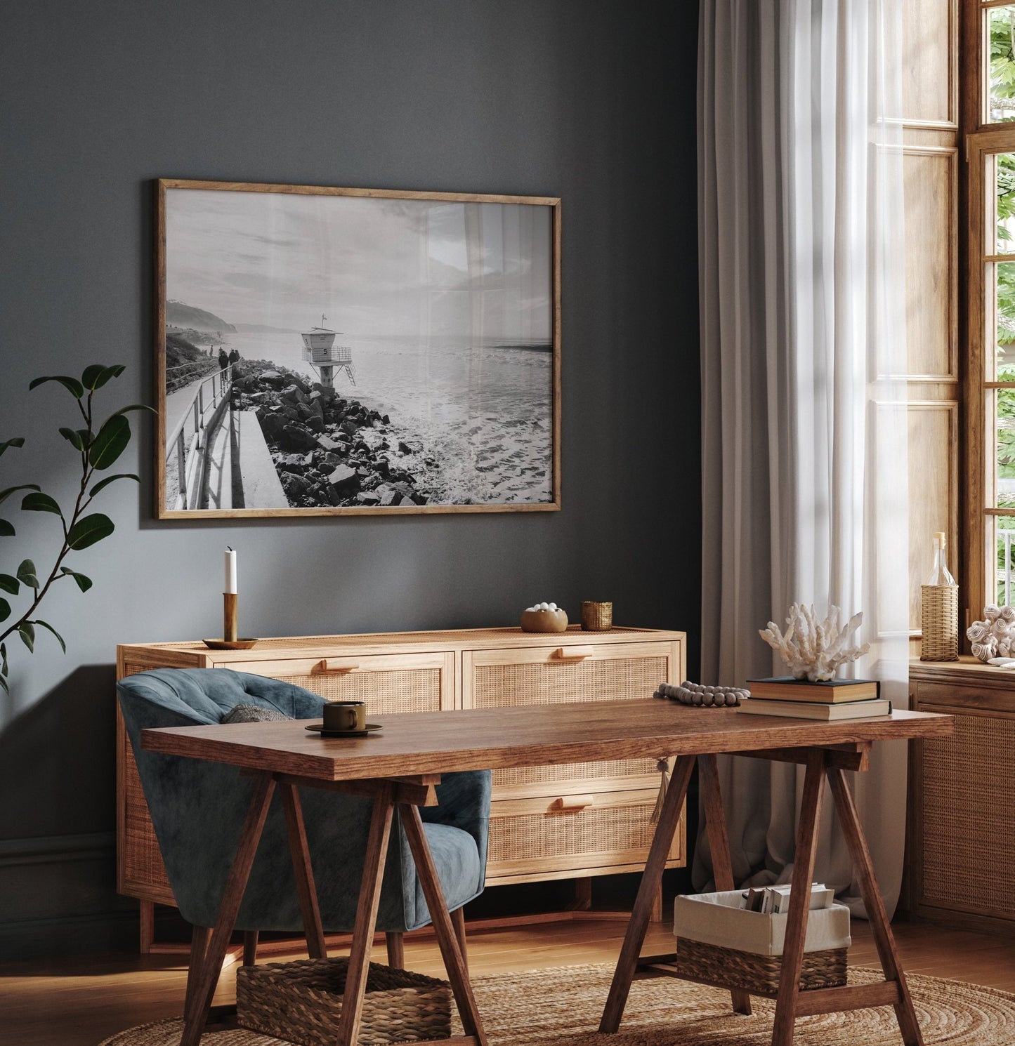 Cozy room with a wooden desk, blue chair, sideboard, large window, and Torrey Pines Black and White photo plus plants.