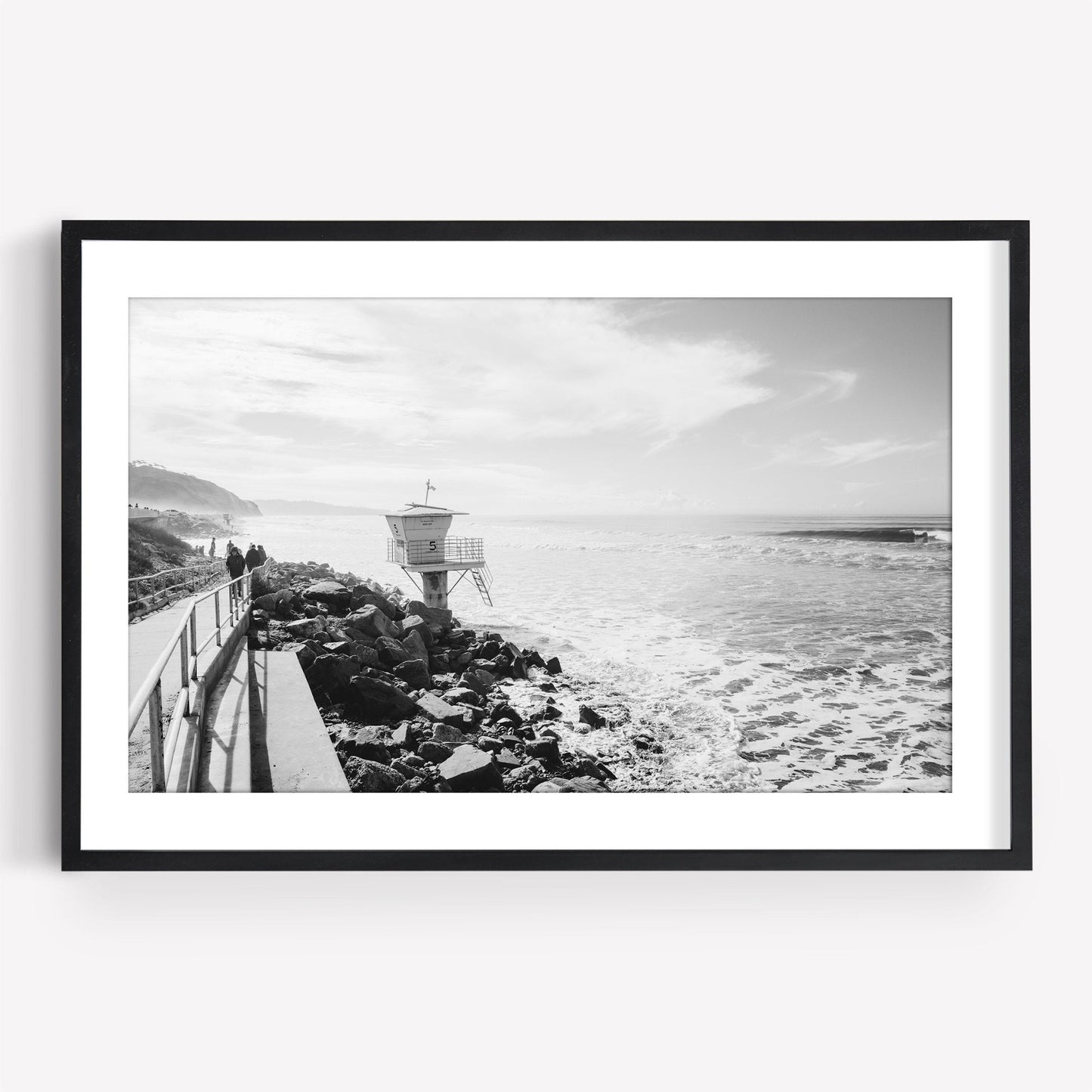 Framed black and white photo named Torrey Pines, featuring a lifeguard tower by a rocky beach with waves and cliffs.