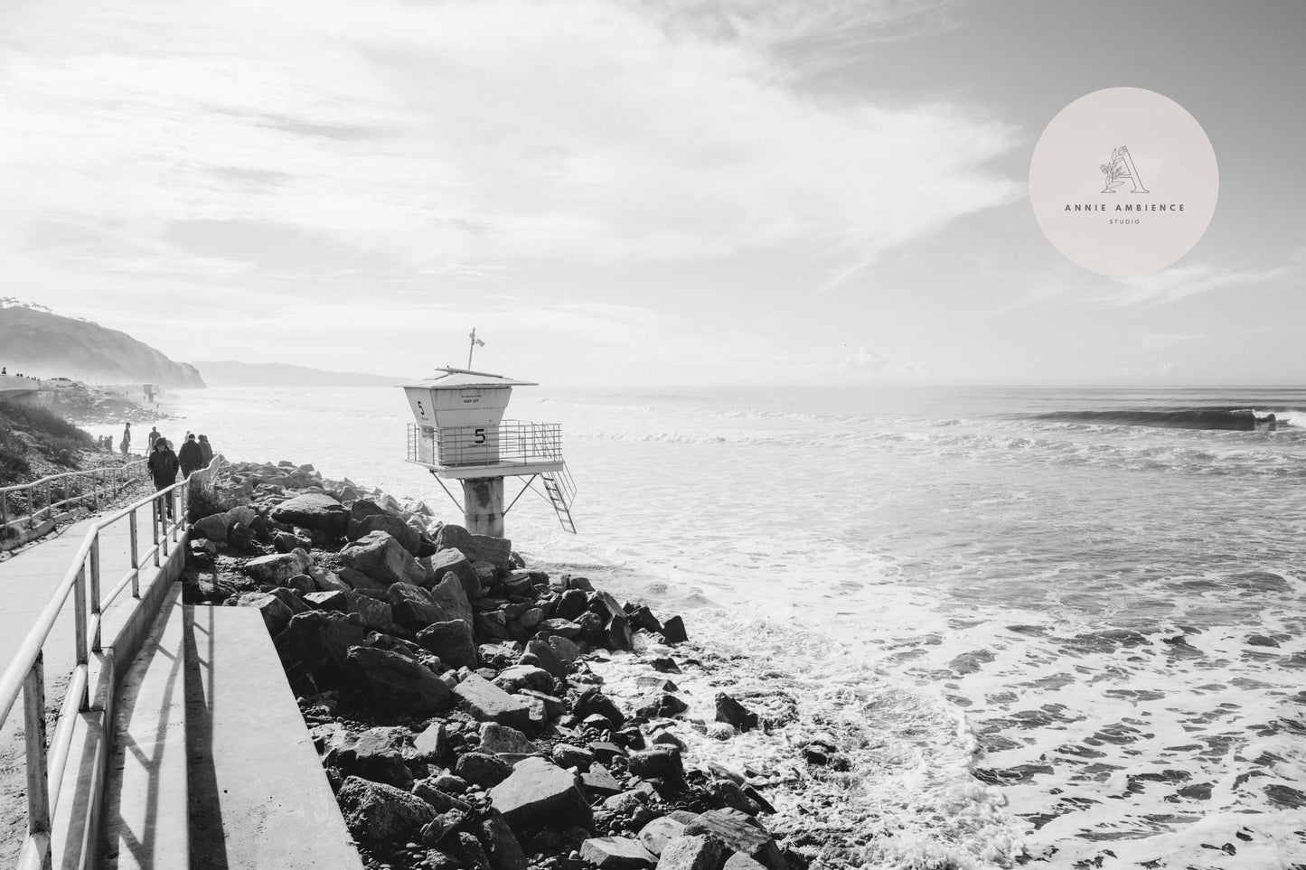 Torrey Pines Black and White photo of a coastal path, rocky shore, and lifeguard tower under a cloudy sky.