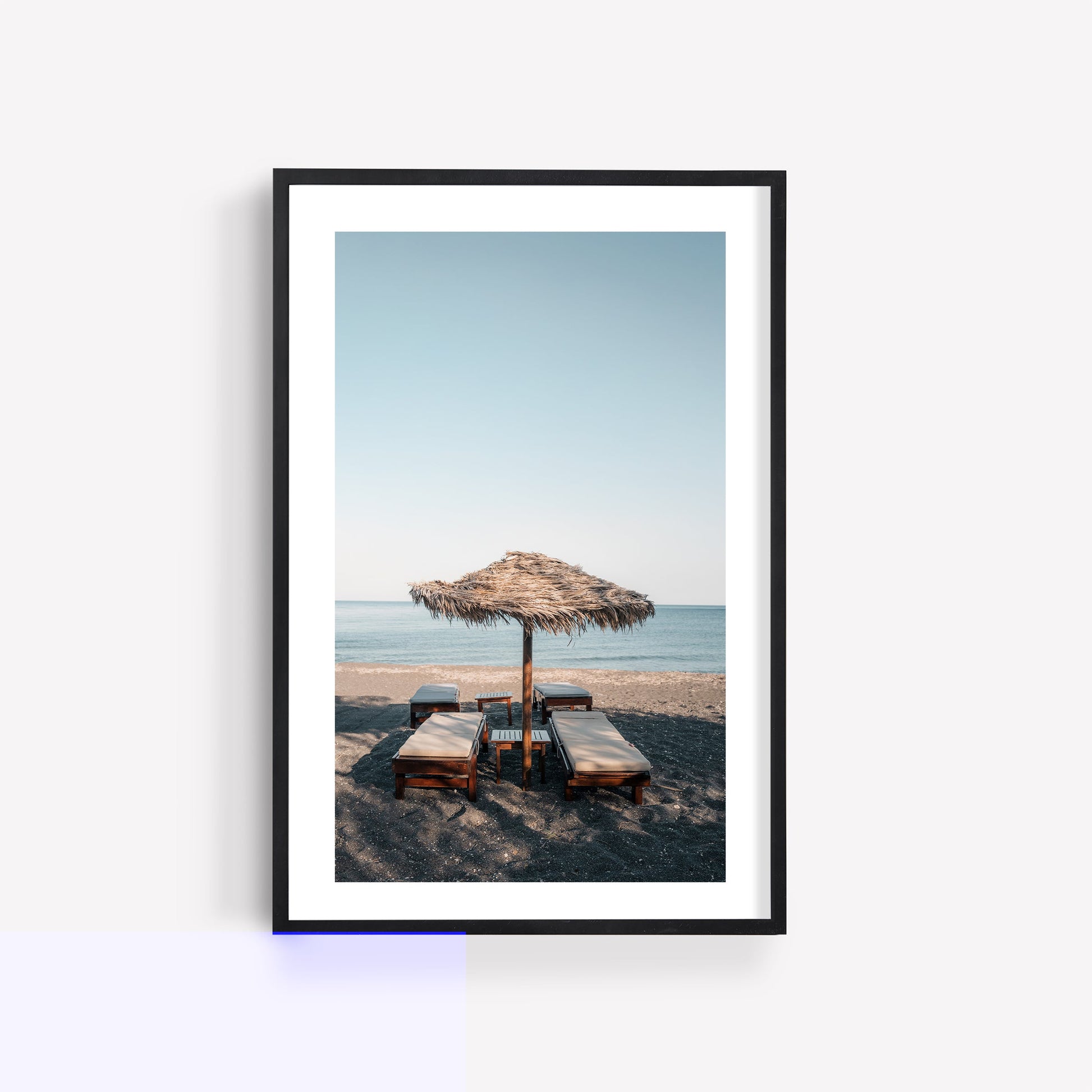 Tranquil Shade: Framed photo of four lounge chairs under a thatched umbrella, facing the serene sea.