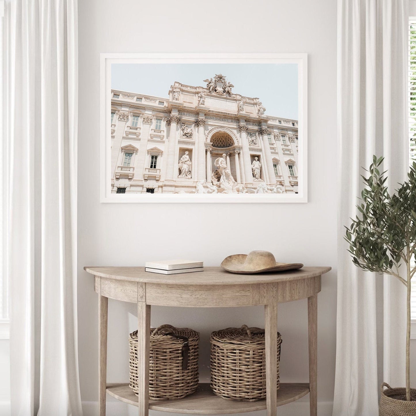 Framed photo of Trevi Fountain above a console table with baskets and a plant.