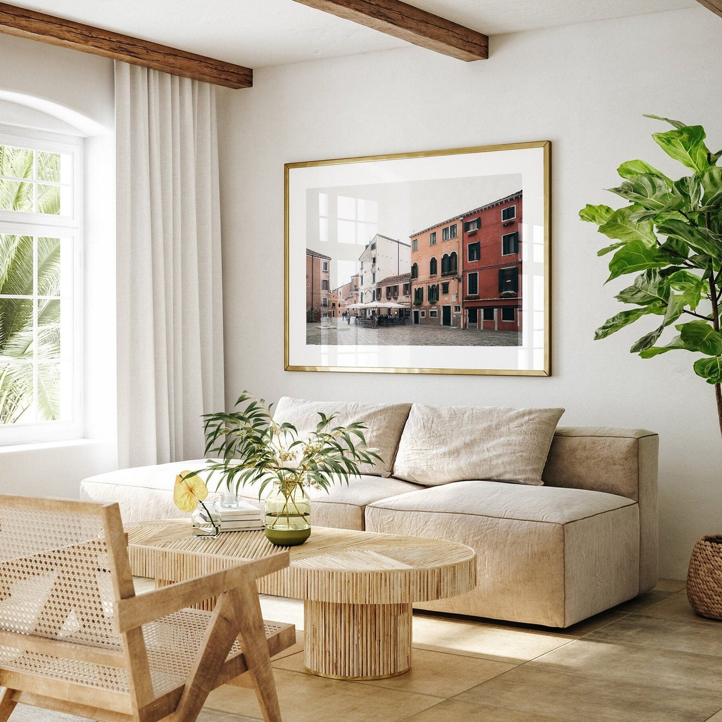 Living room features the Venice Piazza beige sofa, a large photo, wooden furniture, and a tall plant near the window.