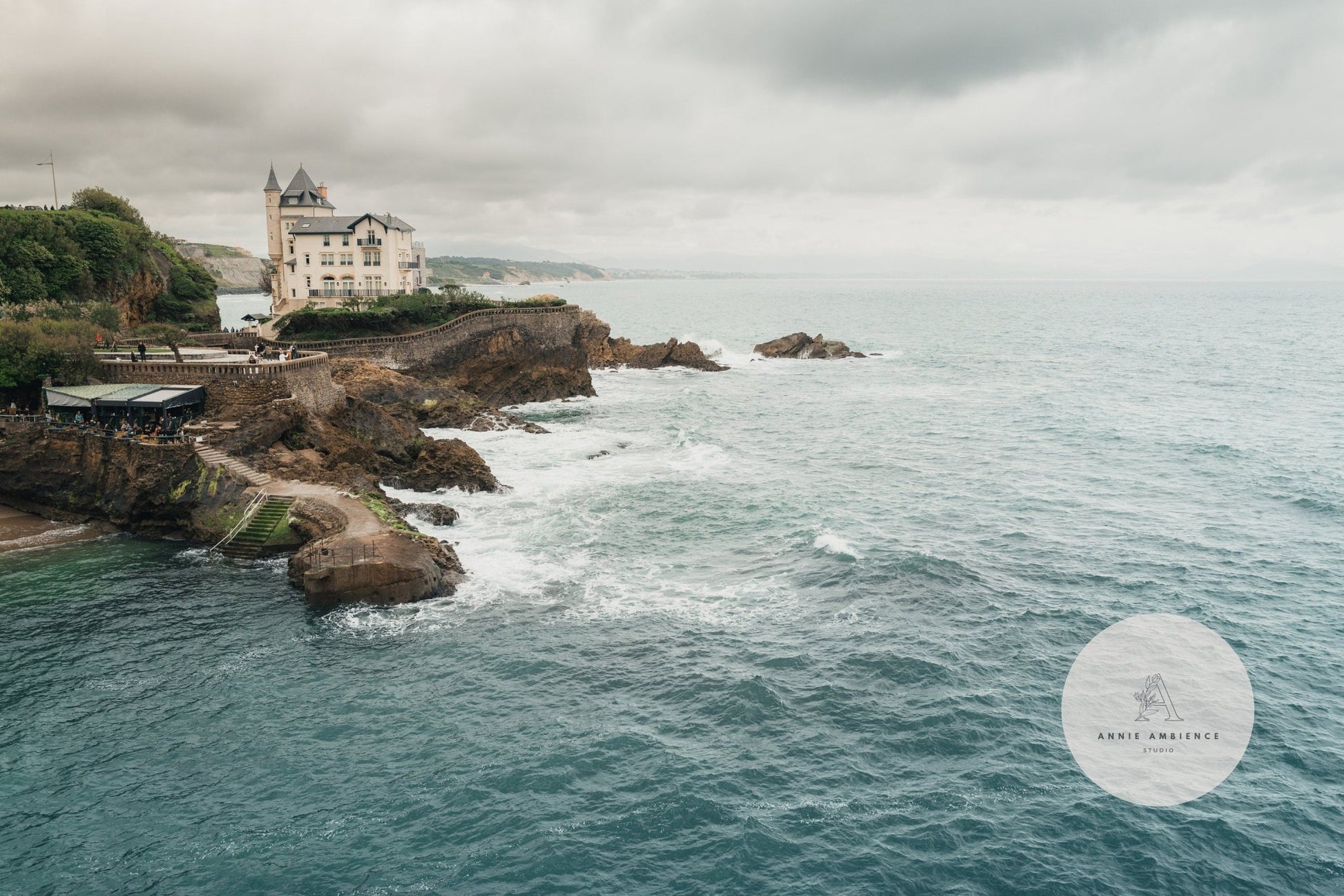 Villa Beltza: A historic coastal villa perched on a cliff, offering views of waves crashing under a cloudy sky.