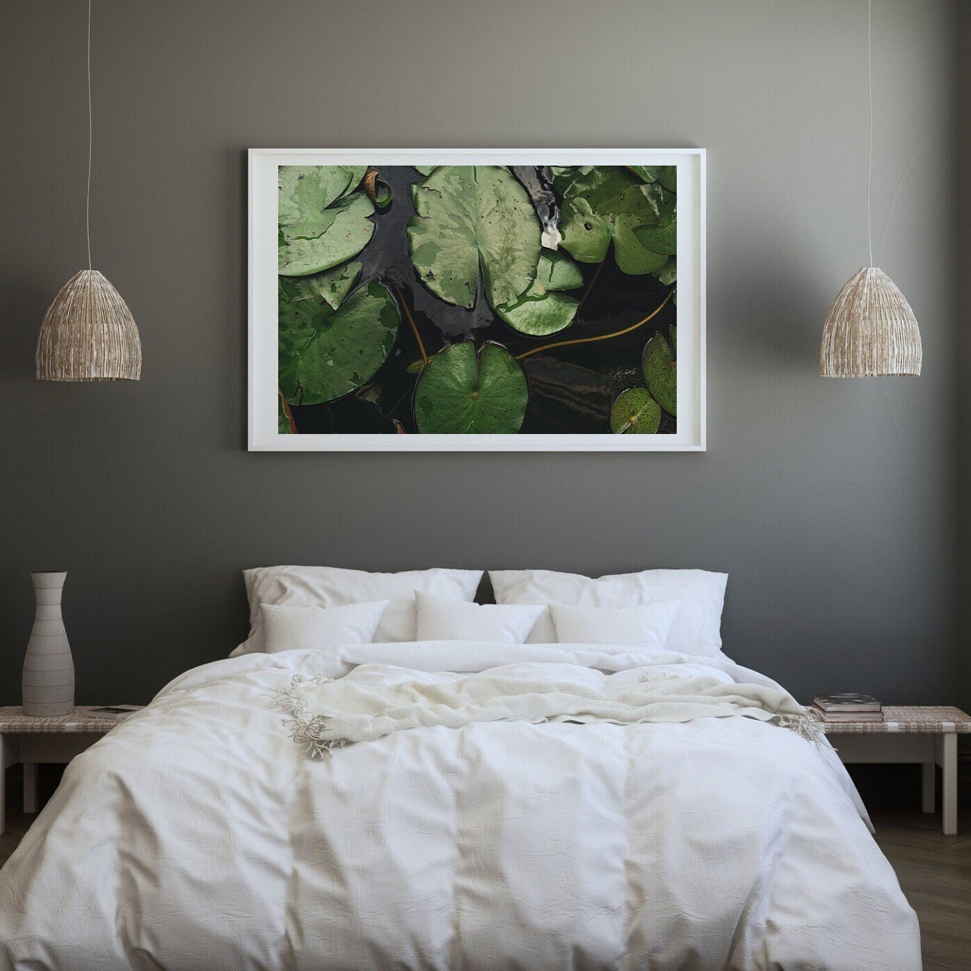 A cozy bedroom features a white bed, wicker lamps, and a large framed Waterlilies photo above the bed.