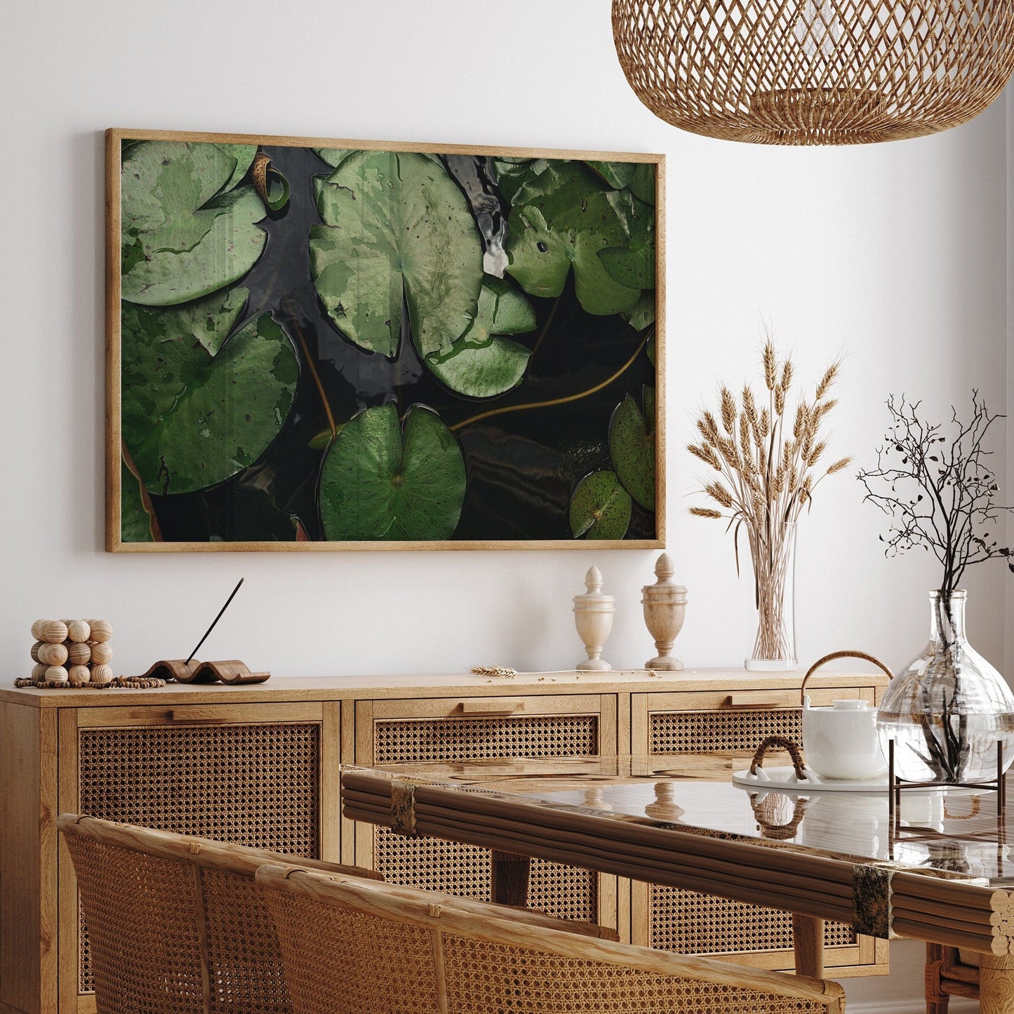 Dining room with a wicker table and chairs, Waterlilies photo on the wall, and decor items on the sideboard.