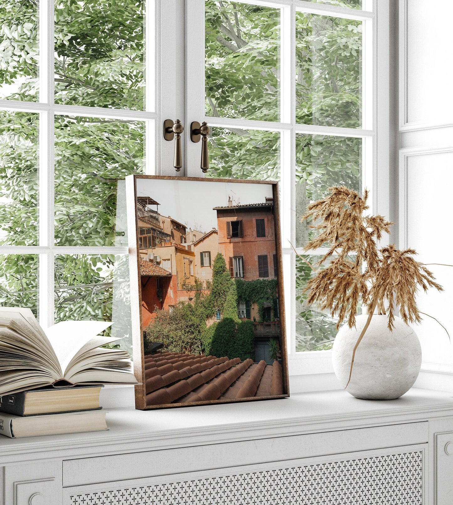 Woke Up in Rome cityscape photo on windowsill with open book, dried plant, and lush greenery view.