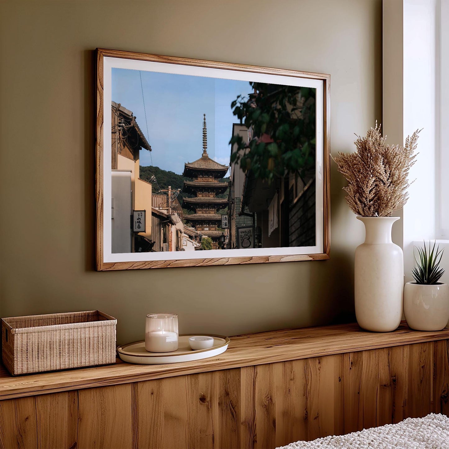 The Yasaka Splendor artwork, beautifully framed, is displayed on a wooden shelf adorned with candles, vases, and a basket.