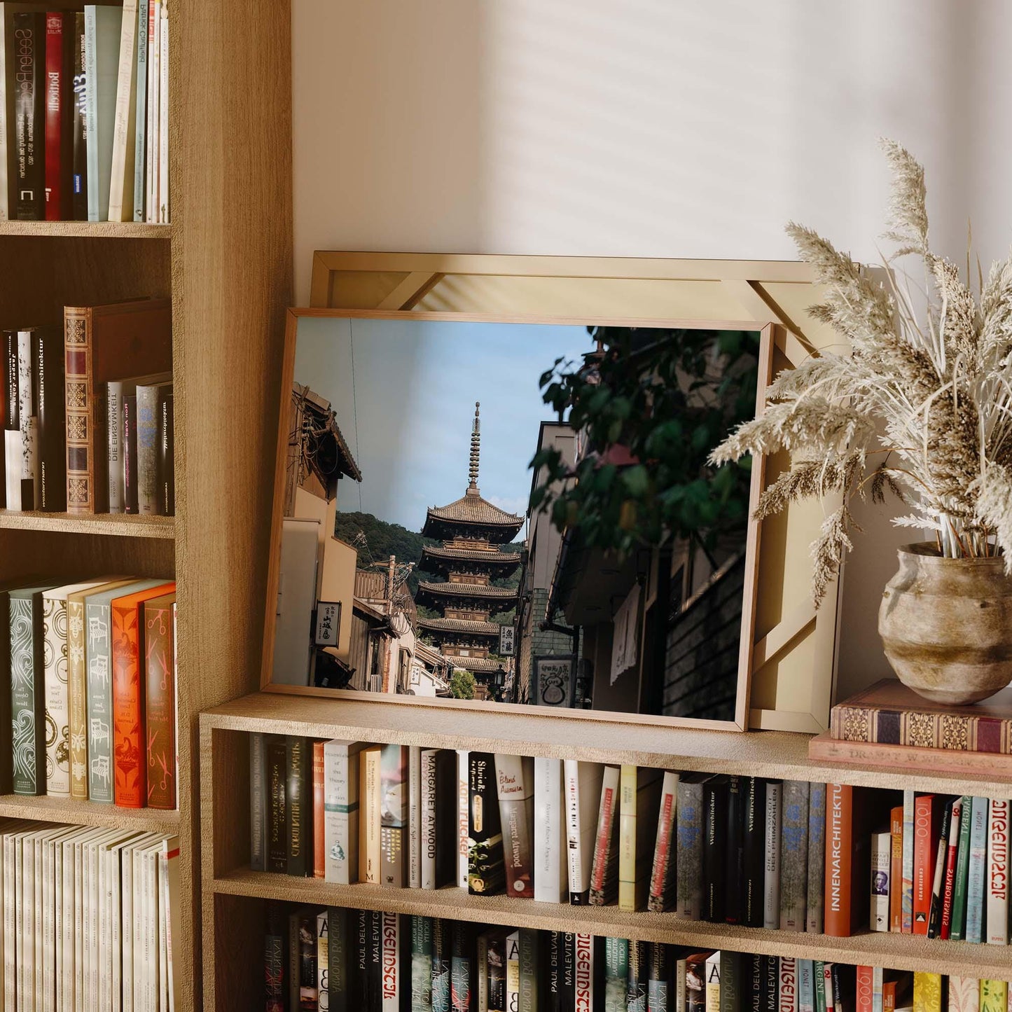 The Yasaka Splendor bookshelf features a framed pagoda photo, assorted books, a vase with dried plants, and is beautifully lit by soft natural light.