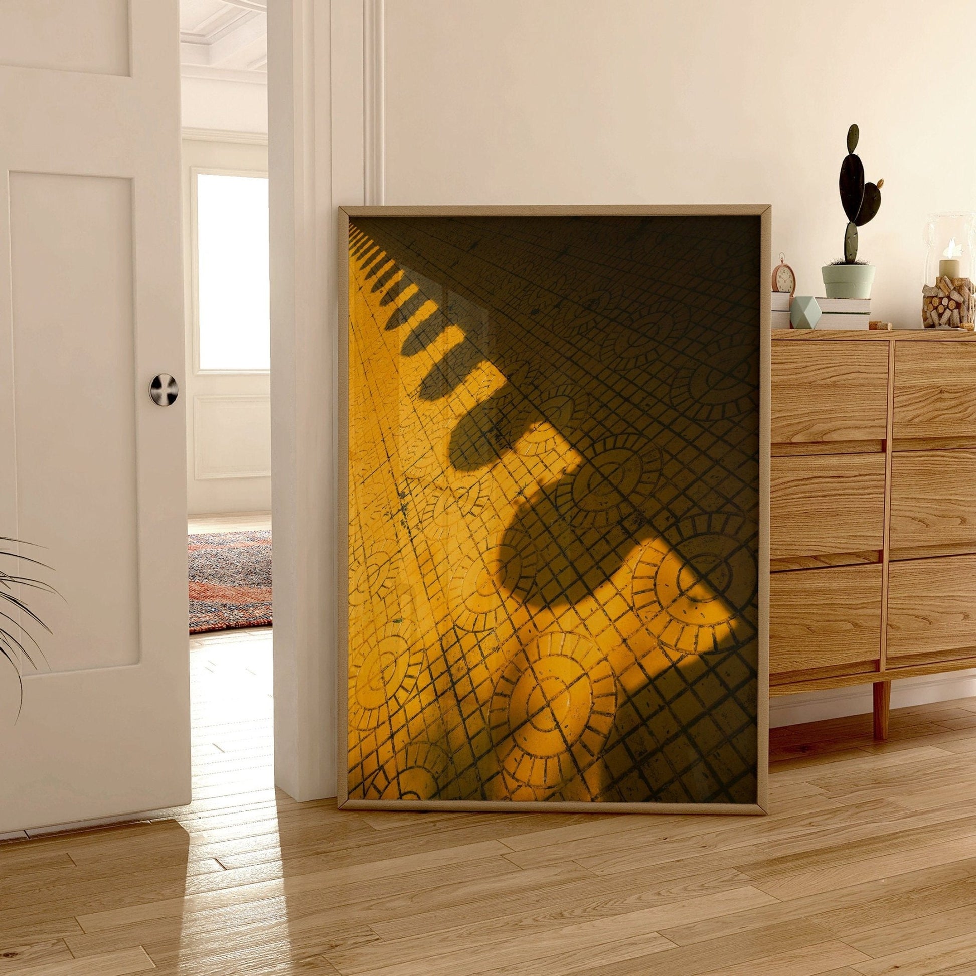 Yellow Harmony geometric art with circular patterns placed on wood floor by a wooden dresser and open door in bright room.