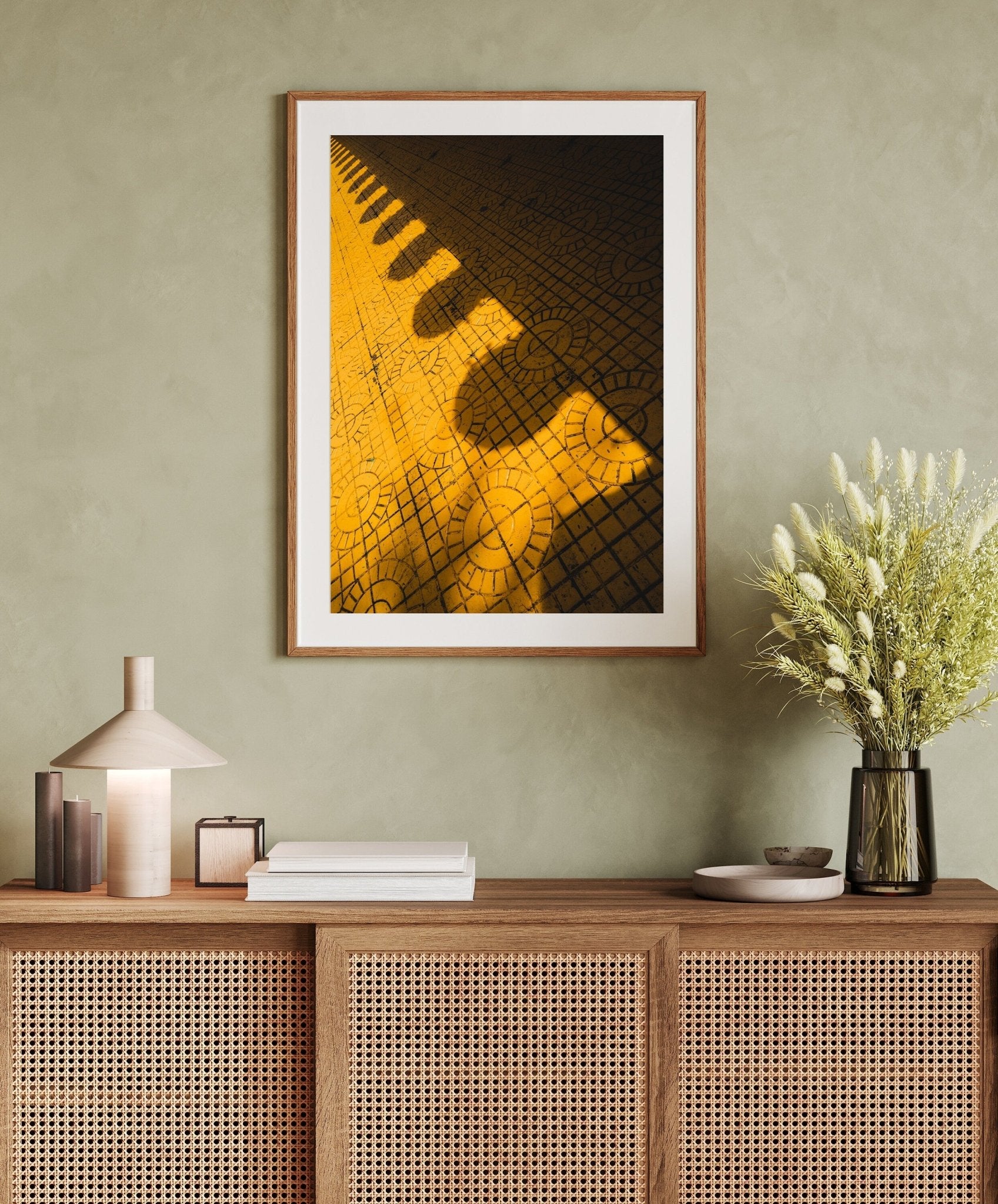 Yellow Harmony artwork on a beige wall above a wooden console with a lamp, books, and a potted plant.
