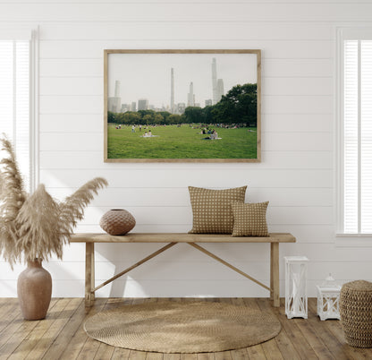 Neutral-toned room with a wooden bench, woven decor, and the "Great Lawn" wall art depicting skyscrapers in a city park.
