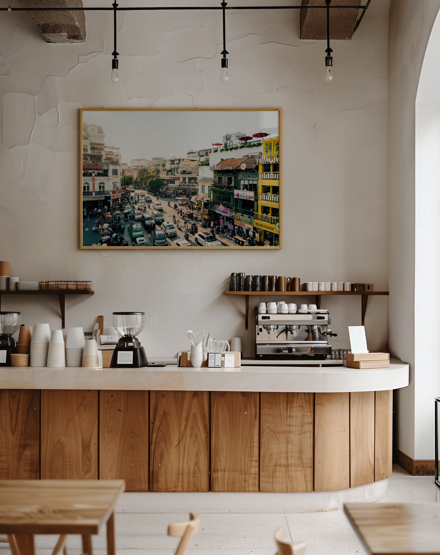A modern coffee shop counter with coffee machines, cups, and the "Streets of Hanoi" photo on the wall above.