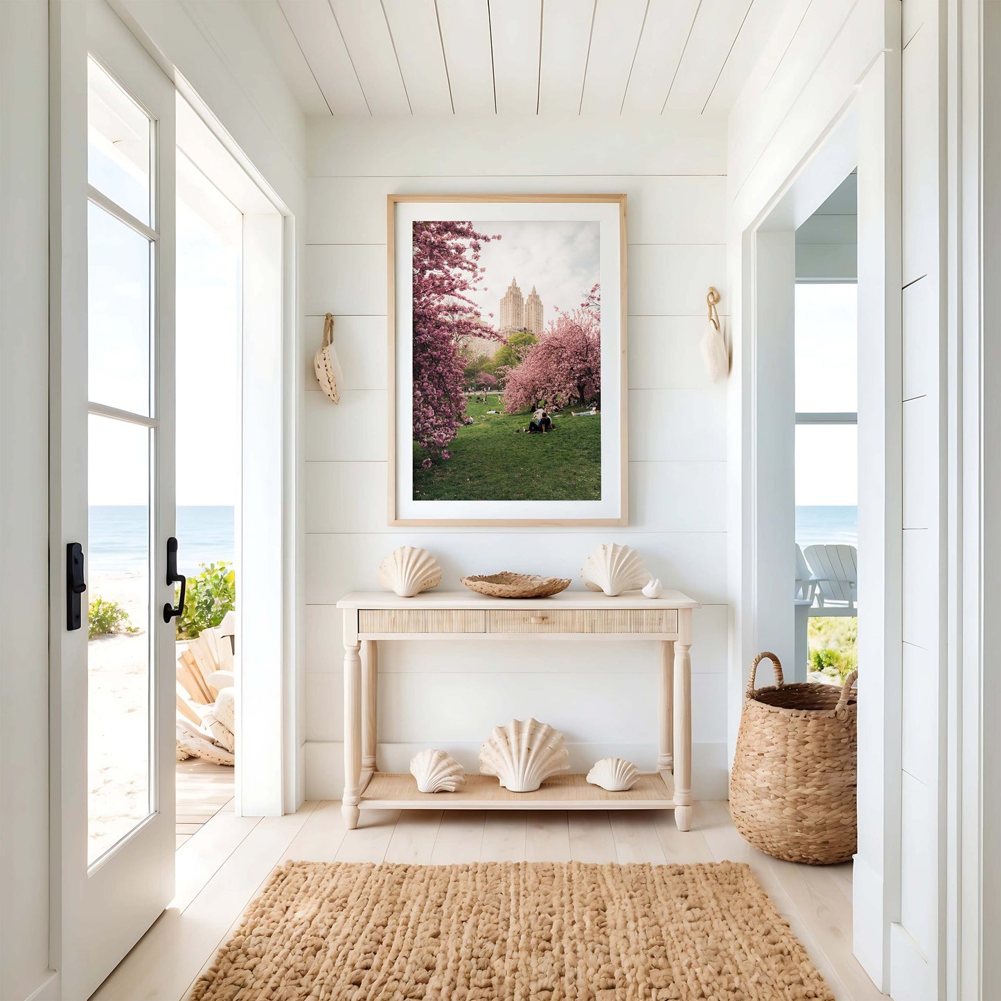 Bright coastal entryway with a light wood console, seashell decor, woven rug, and Cherry Blossom I wall art.