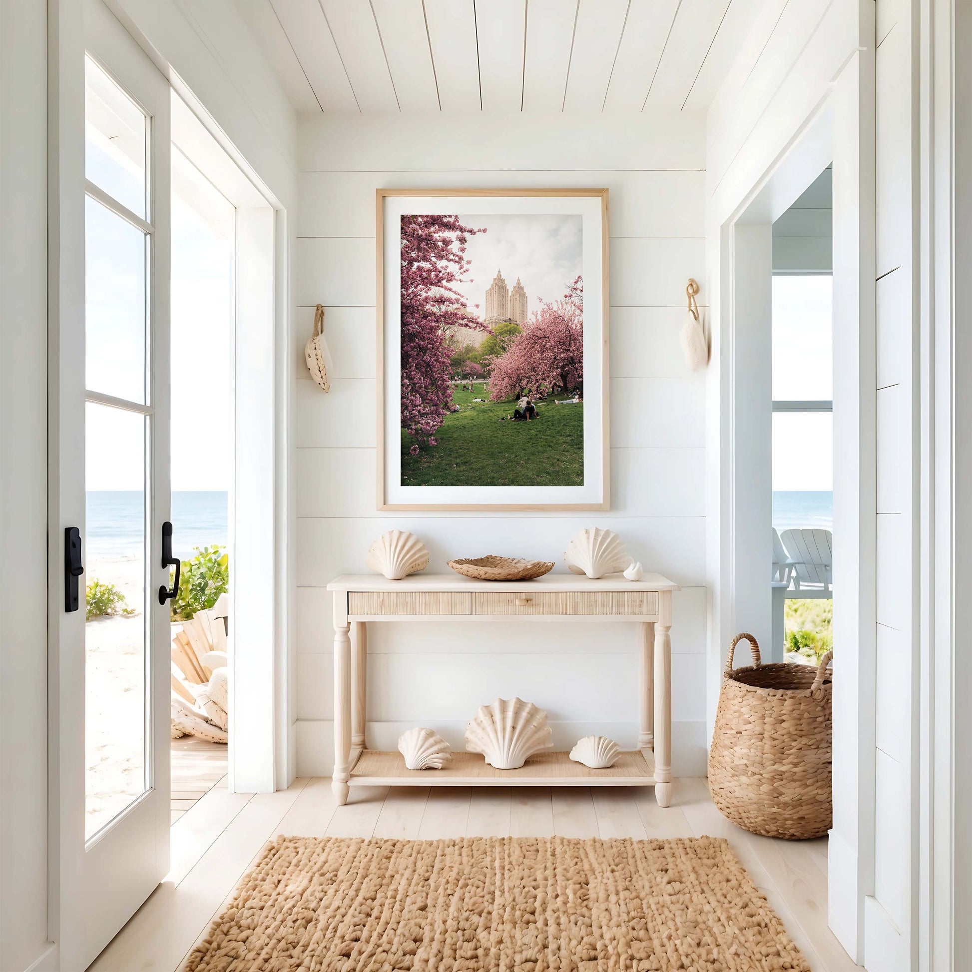 Bright coastal entryway with a light wood console, seashell decor, woven rug, and Cherry Blossom I wall art.