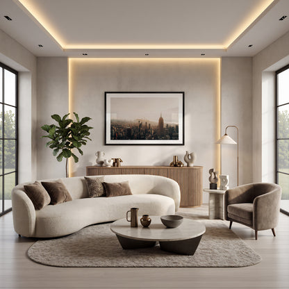 Modern living room with curved white sofa, gray armchair, coffee tables, plants, and NYC Skyline artwork on the wall.