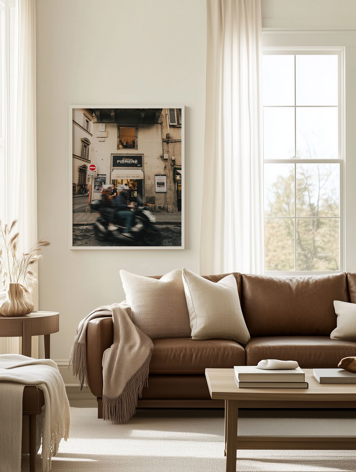 A cozy living room featuring the Florence Motorcycle wall art above a brown leather sofa, coffee table, and throw pillows.