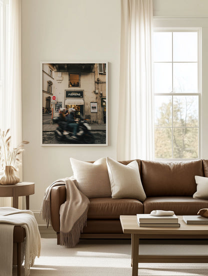 A cozy living room featuring the Florence Motorcycle wall art above a brown leather sofa, coffee table, and throw pillows.