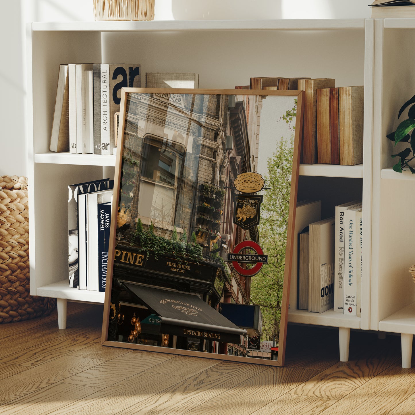 A framed print of The Porcupine Pub leans against a bookshelf in a cozy room with wooden floors.