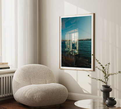 Curved white chair beside table and vase, with “Almada Reflections” framed on a sunlit wall.