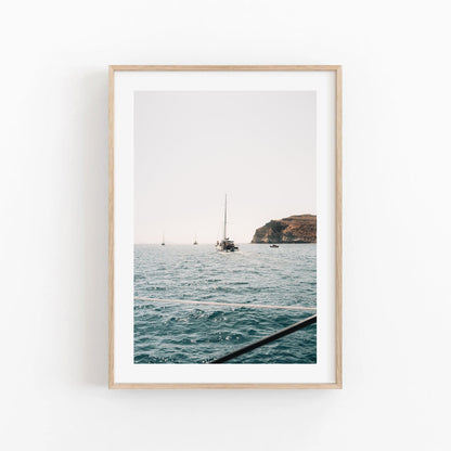 Framed photo, Afternoon Sail I, features a sailboat on the ocean with a rocky coastline backdrop.