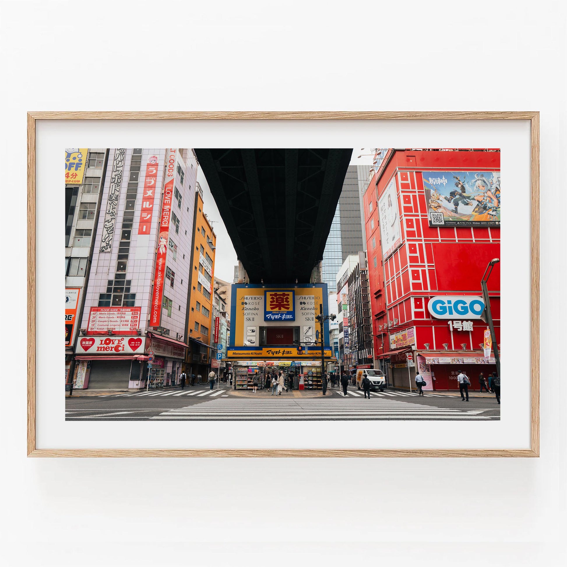 Akihabaras vibrant cityscape features colorful buildings and billboards, with people crossing the street under an elevated structure.