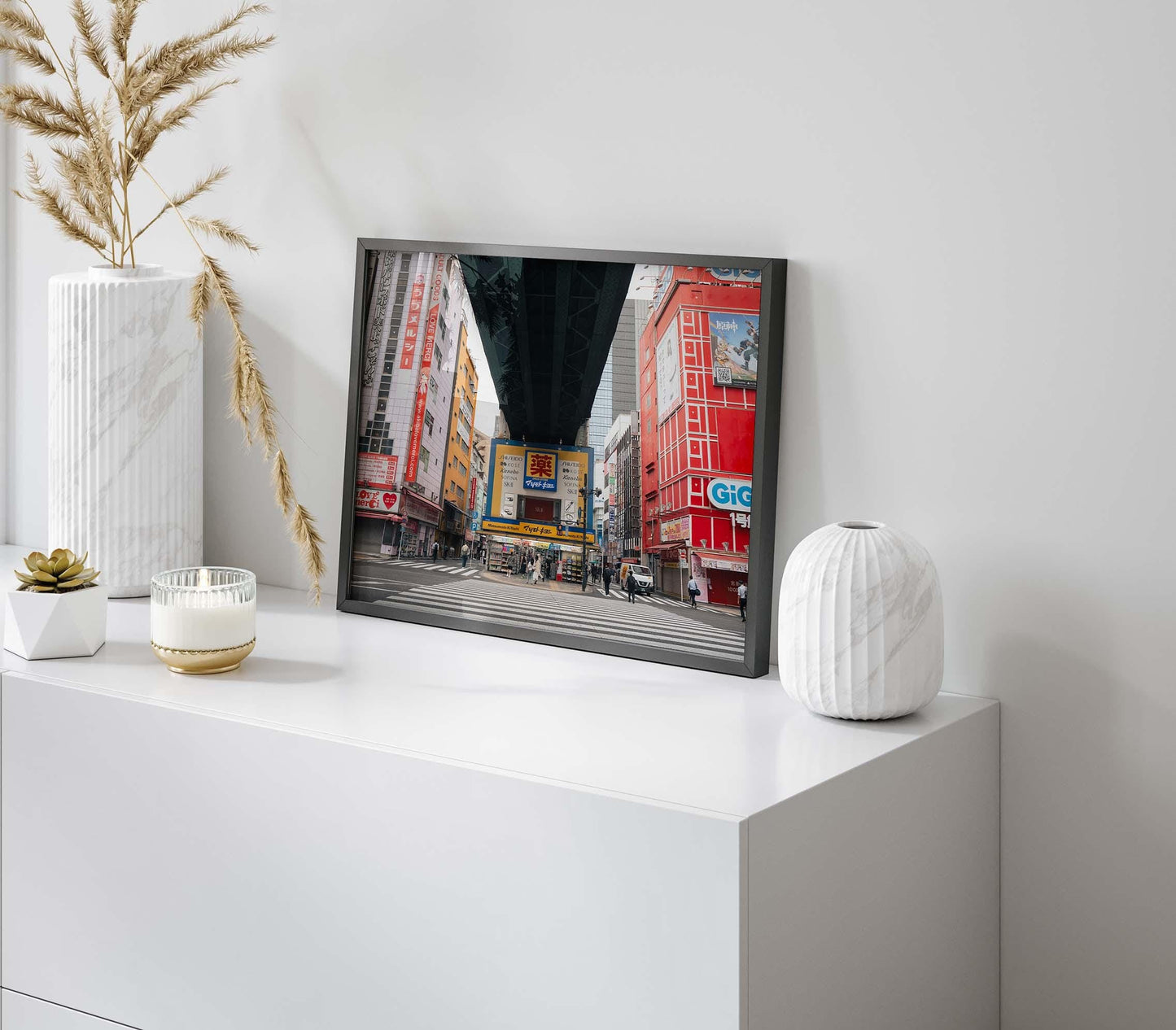 The framed Akihabara photo sits on a white cabinet, accented with vases and a candle.