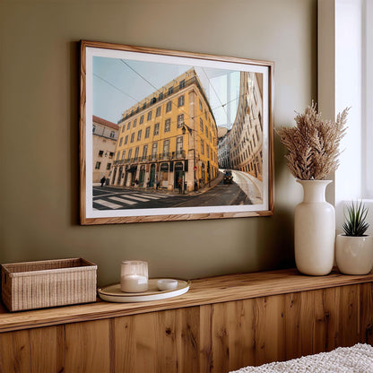 Baixa-Chiado framed photo of a yellow city building hangs above a wooden console with vases, candles, and a basket.