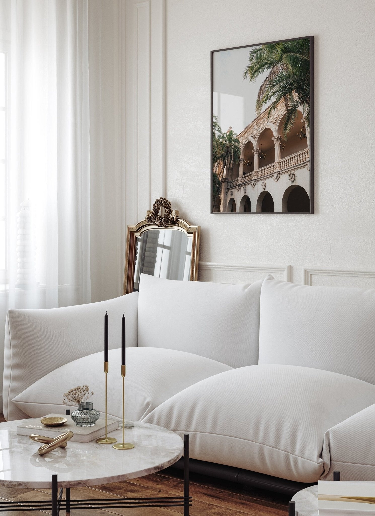 Elegant living room with a white sofa, marble table with black candles, Balboa Architecture I photo, and a mirror.