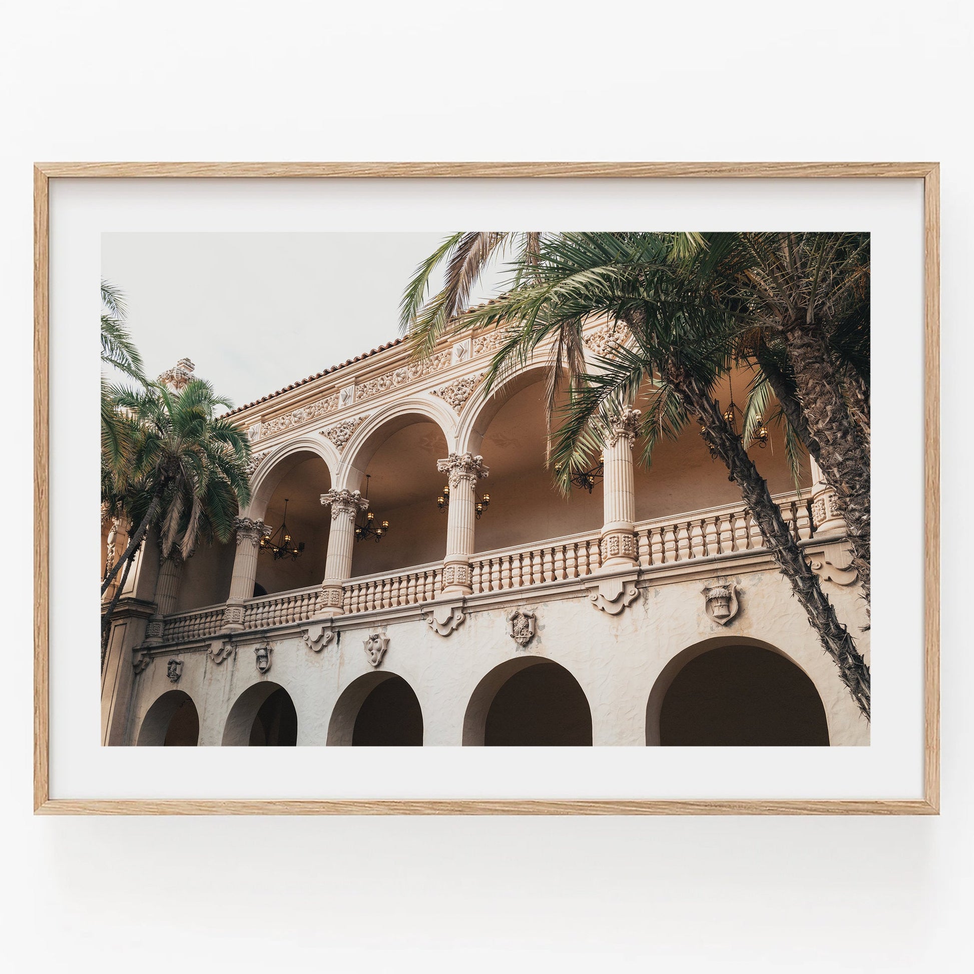 Framed Balboa Architecture II photo of an elegant building with arches and palm trees on a white background.