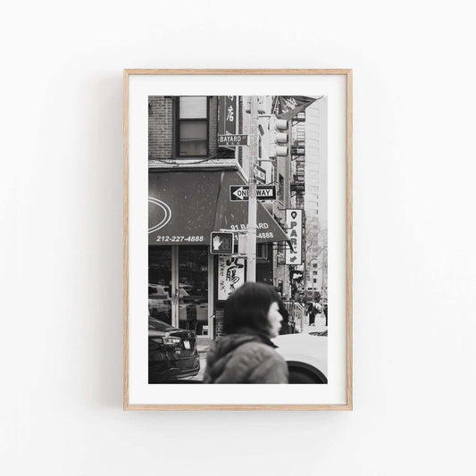 Framed Bayard St. Black and White street photo with a blurred person in the foreground and city signs in the background.