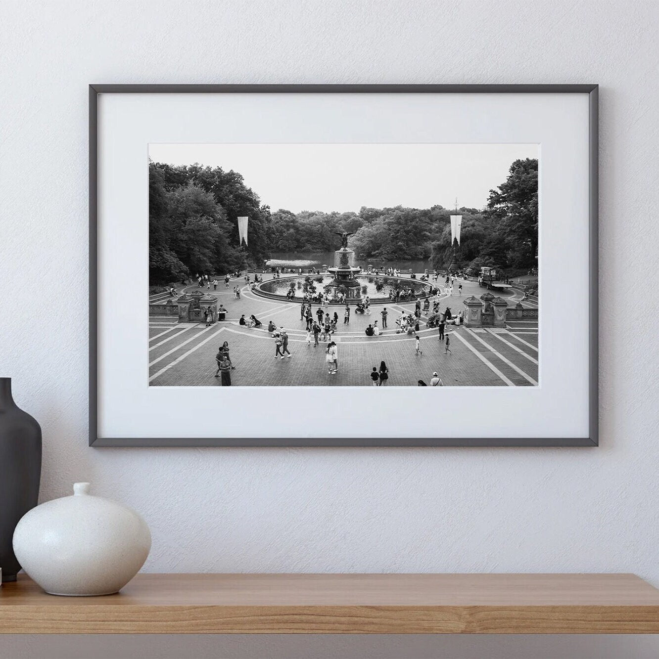 Bethesda Fountain Black and White photo on a white wall above a wooden shelf.