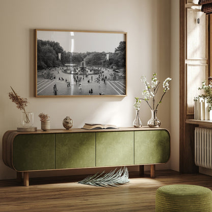 A cozy room with green furniture, the Bethesda Fountain Black and White photo, and flower vases on a wooden sideboard.