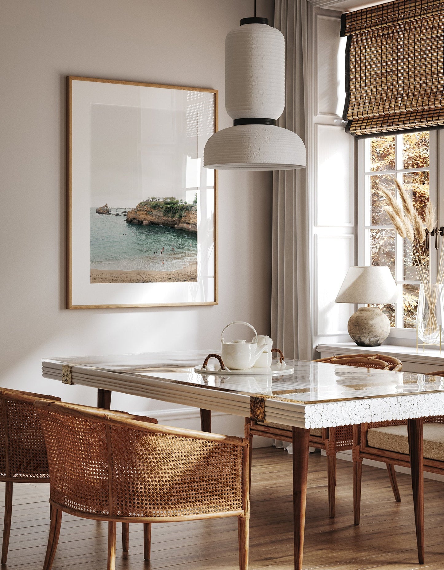 Minimalist dining area with marble table, wicker chairs, a white pendant light, and Biarritz Beach II on the wall.