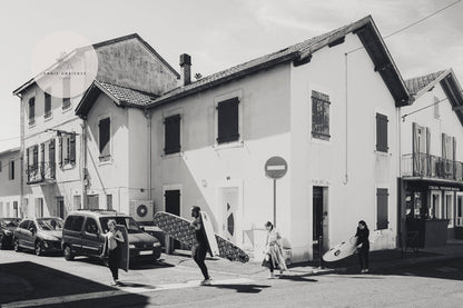 Surfers carrying boards pass a building in Biarritz Surfers Black and White print.