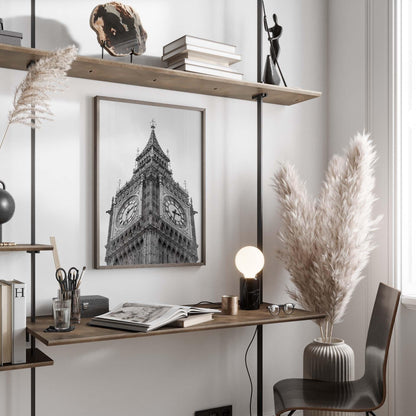 Modern home office with a Big Ben Black and White photo, wooden desk, shelves, pampas grass, and a glowing lamp.