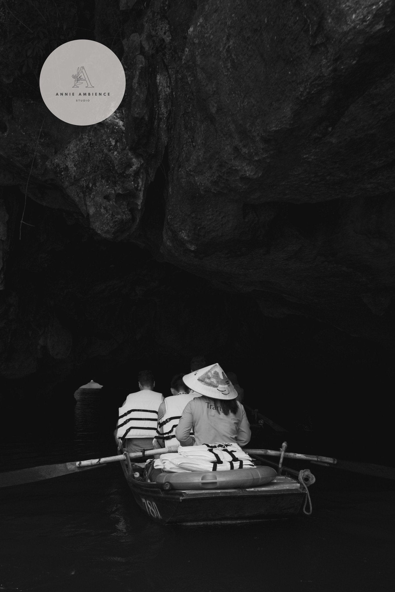 People rowing into a cave in hats and life jackets, featuring black and white Vietnam Bamboo - Set of 3.