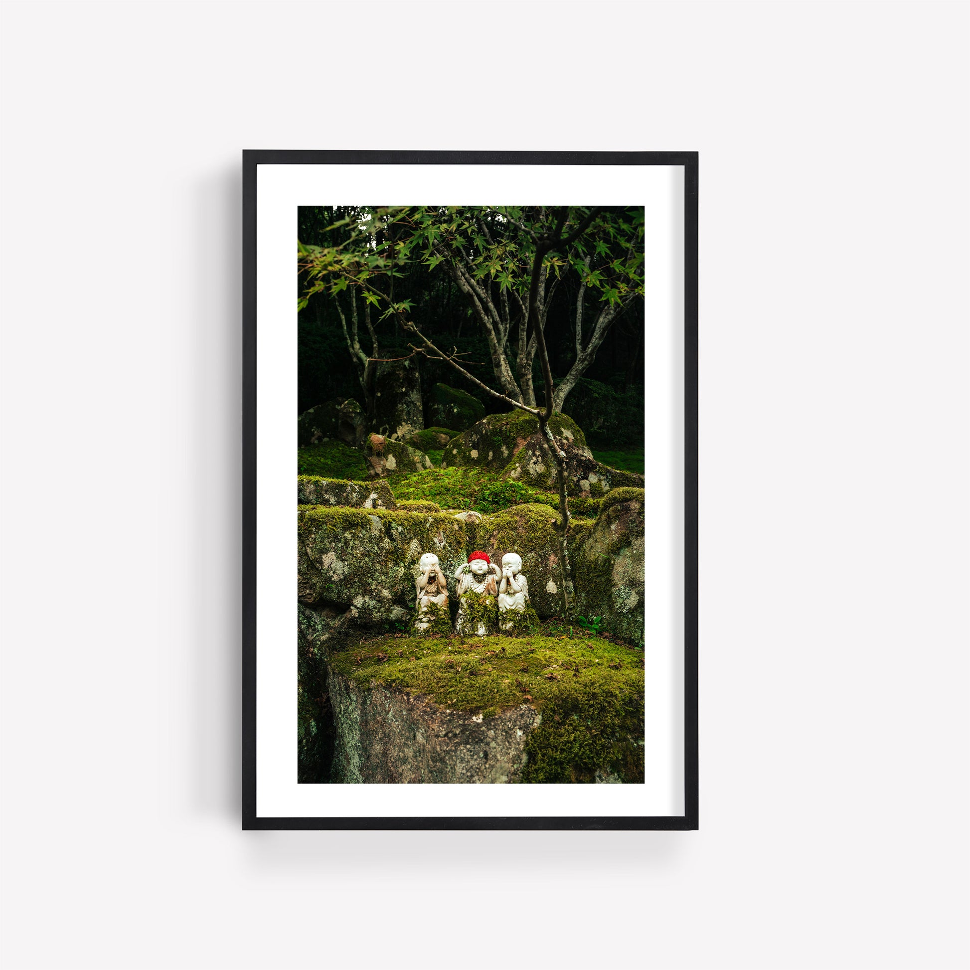 Framed photo titled Three Wise Ones depicting a serene stone garden with statues on moss-covered rocks under trees.