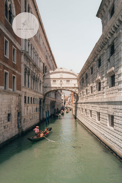 Gondolas glide through a narrow canal in Venice beneath the Bridge of Sighs, flanked by historic buildings.