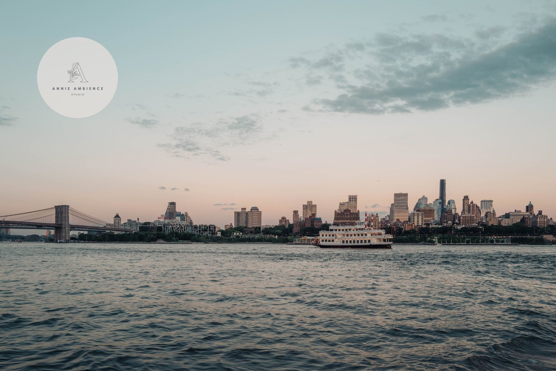 Brooklyn Sunset captures a ferry on the river with the city skyline and bridge against a cloudy dusk sky.